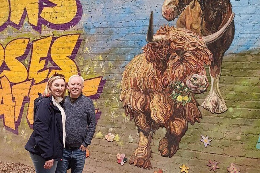 Un murale raffigura un grande animale peloso con un fiore in bocca, una persona e un'altra con il volto sfocato. 4