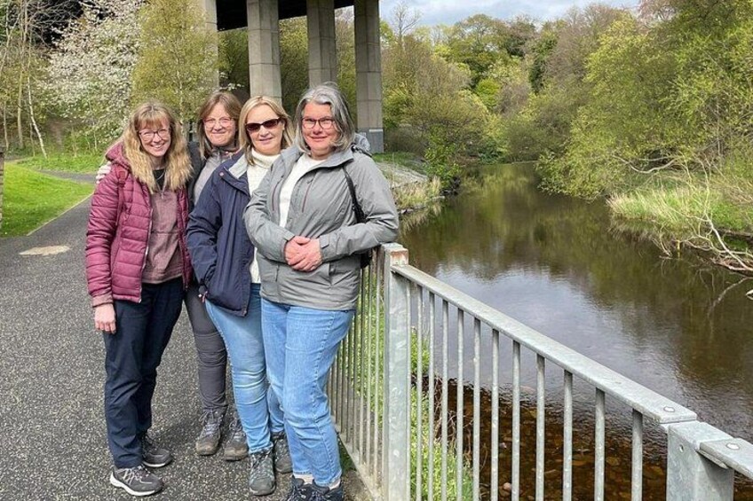 A group of people standing on a bridge over a river. 2