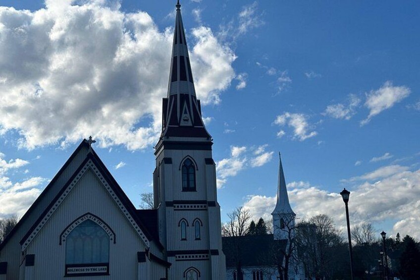 En kyrka med ett högt torn och en mindre spir, under en delvis molnig himmel. 3