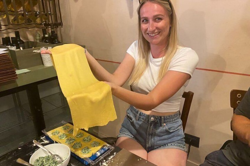 Una persona sosteniendo un paño amarillo, sentada a una mesa con un bol de hierbas verdes y un paquete de pasta. 1