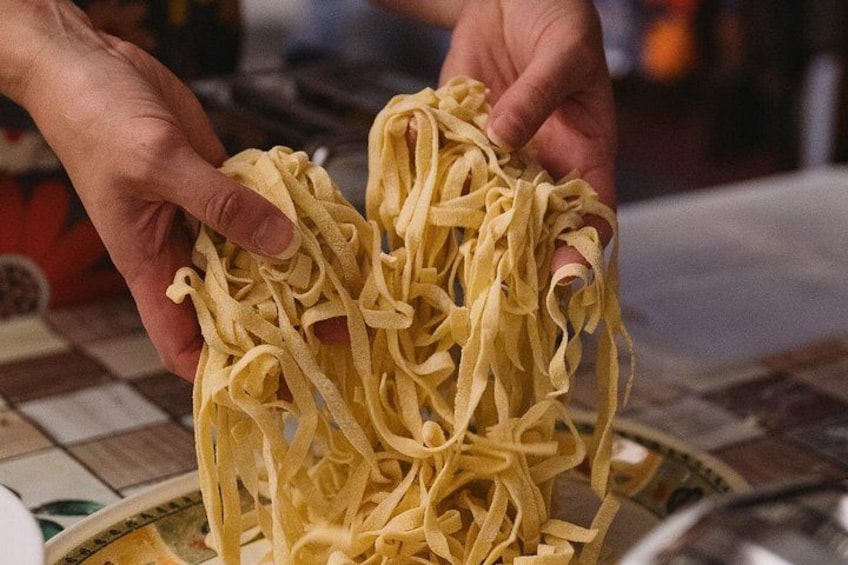 Una persona sosteniendo un manojo de pasta. 3
