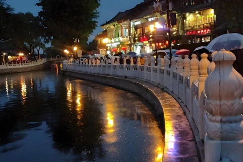 A curved bridge with ornate railings reflecting lights from buildings. 3