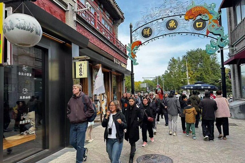 A crowded street with people walking, traditional Chinese architecture, and a decorative archway. 5