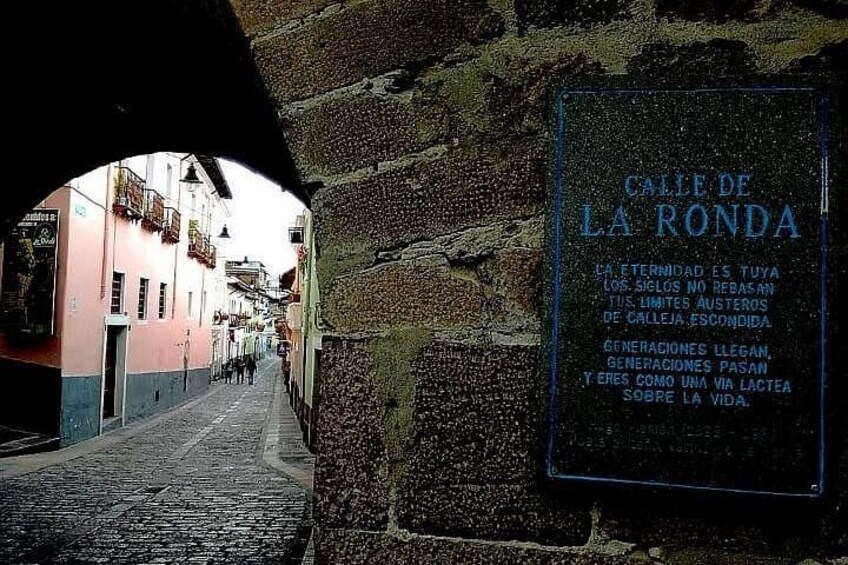 Una calle adoquinada con un muro de piedra y un letrero que dice 'Calle de la Ronda'. 4