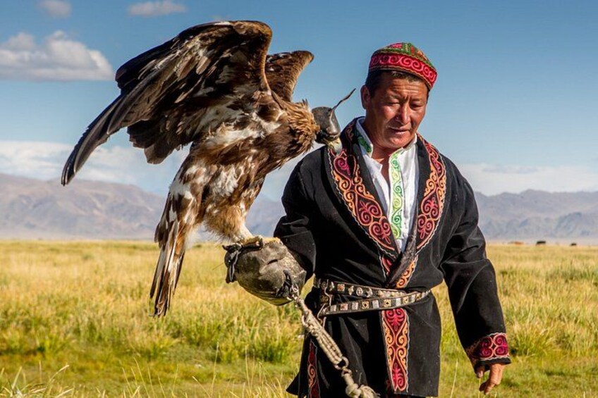 A person in traditional attire holding a bird of prey. 1