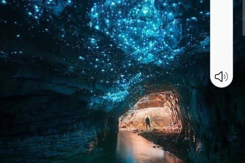 A cave with a person walking through a tunnel illuminated by blue lights. 2