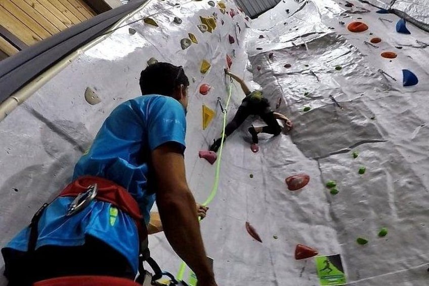 Une personne qui escalade un mur d’escalade intérieur, équipé de prises de différentes couleurs. 1