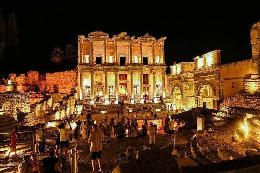 An ancient, illuminated temple complex at night with visitors. 4
