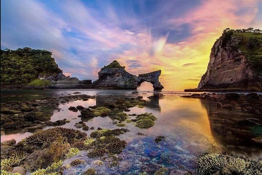Un paisaje costero con un arco de roca, aguas tranquilas y un cielo al atardecer. 4