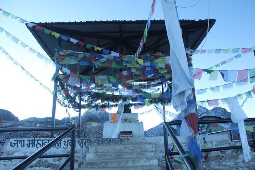 A shrine with colorful prayer flags and a sign in a foreign language. 3