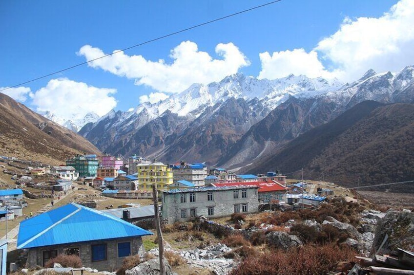 A village with colorful buildings and snow-capped mountains in the background. 1