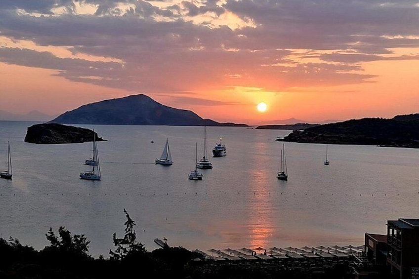 Tramonto su un mare calmo con barche a vela e una montagna in lontananza. 2