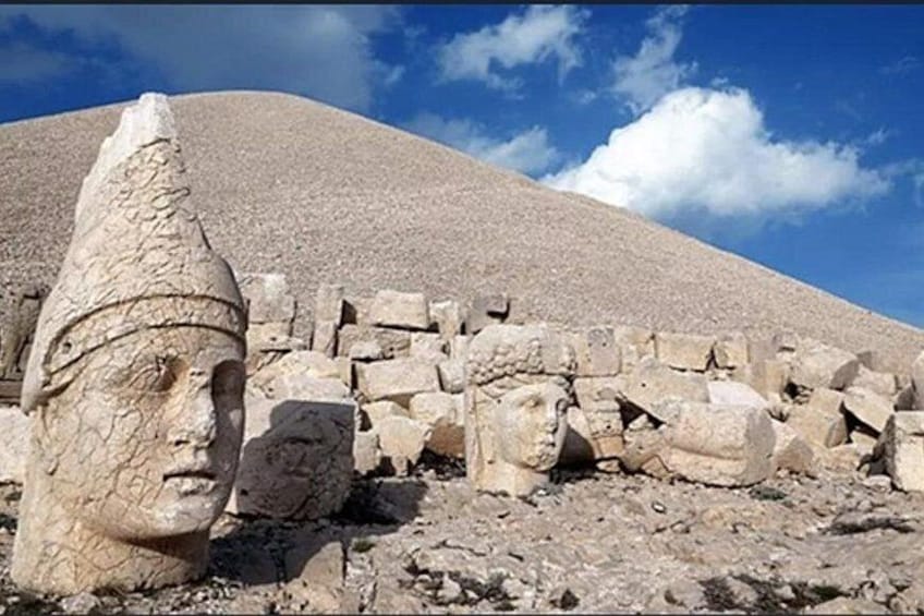 Ancient stone ruins with a large, eroded stone head and fragmented structures. 3