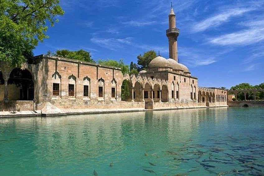 A historic building with a minaret, arched windows, and a pool. 4