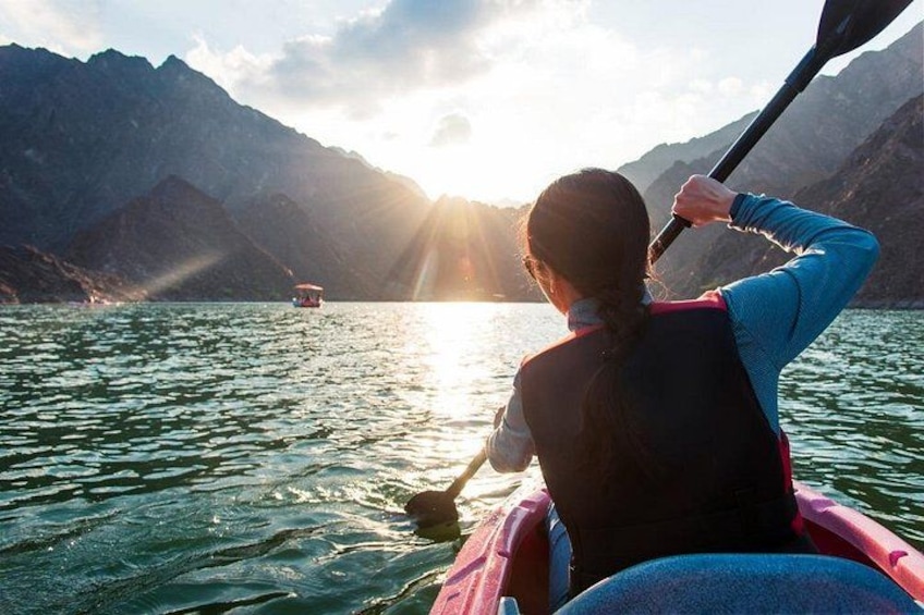 A person kayaking on a calm lake with mountains in the background. 1