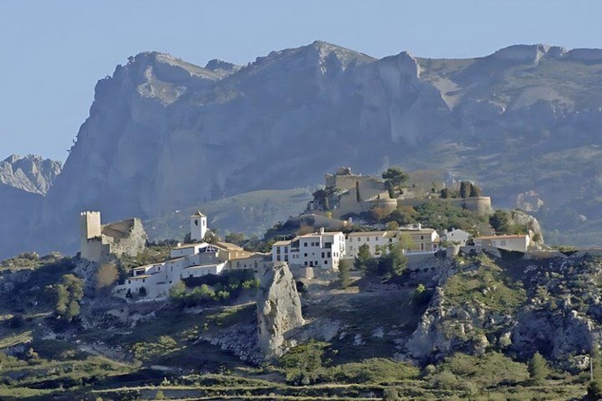 A mountainous village with white buildings, a church, and a castle-like structure. 5