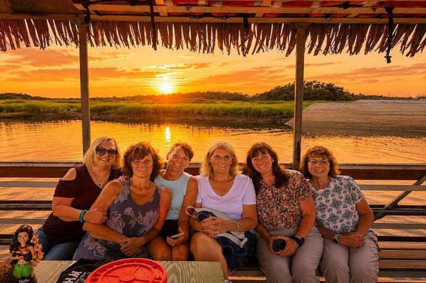 Een groep mensen zit op een houten steiger bij zonsondergang. 4