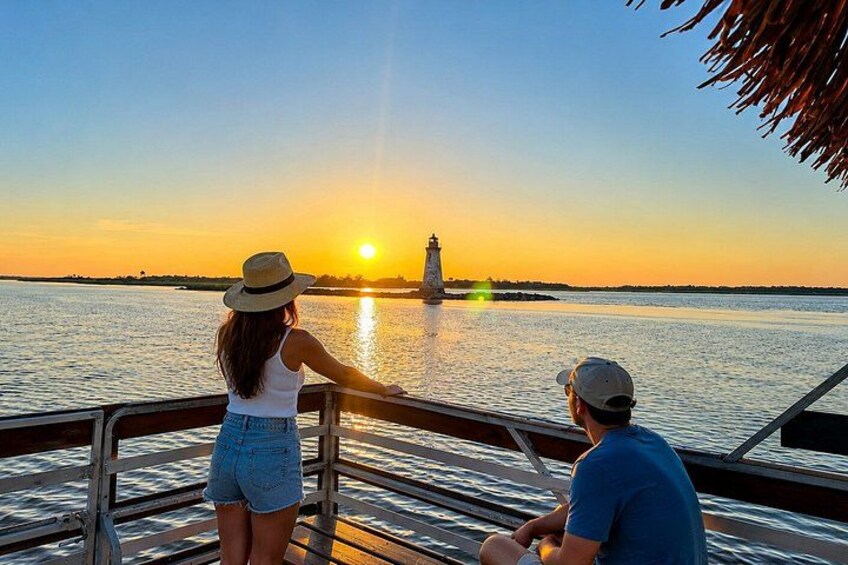 Un atardecer sobre una masa de agua con un faro a lo lejos. 3