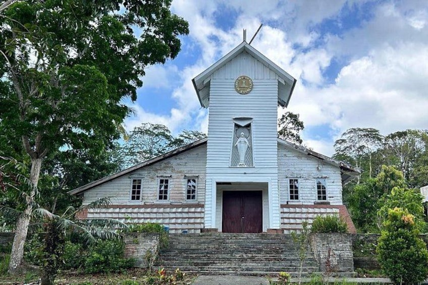 Una iglesia blanca con un campanario, una estatua y una puerta roja. 1