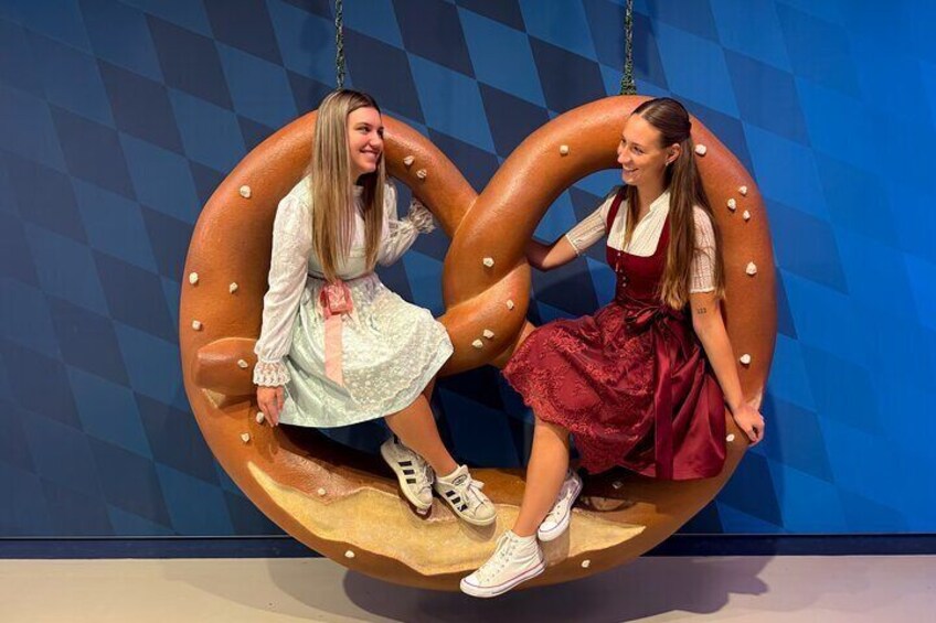 Two people sitting on a pretzel-shaped swing. 1
