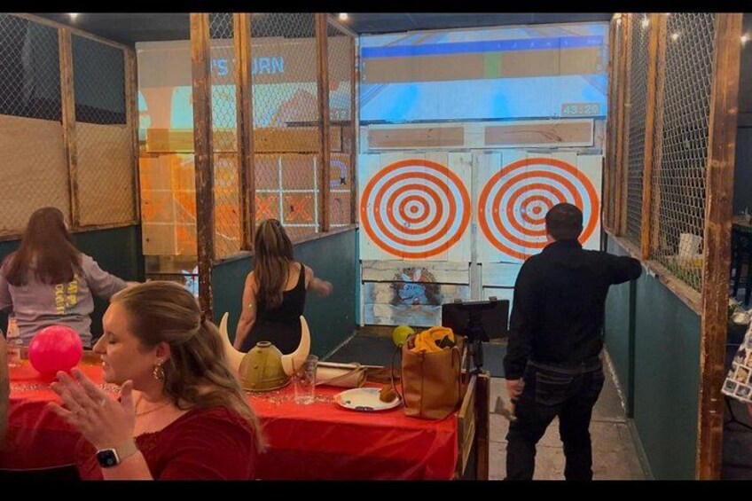 Una habitación con una mesa roja, una persona de pie junto a una ventana y un blanco en la pared. 4