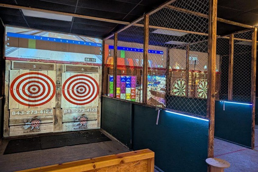 Un dardo en la diana, un banco de madera y, al fondo, una sala recreativa con luces de neón. 2