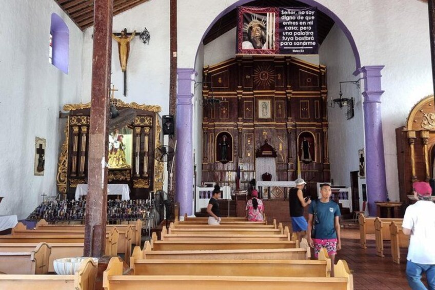 Interior de iglesia con bancas de madera, un crucifijo y un gran altar. 3