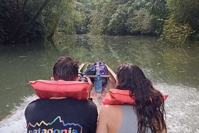 Two people on a boat with life jackets, surrounded by greenery and water. 5