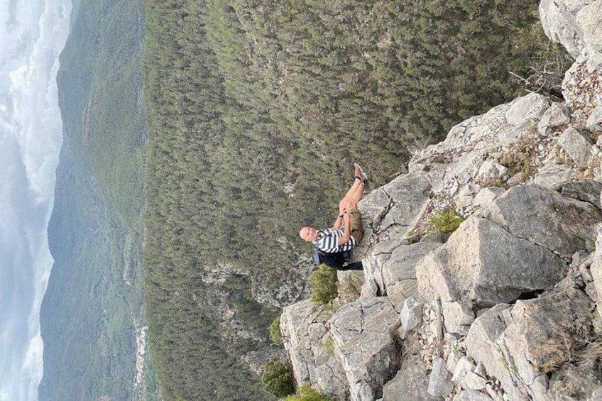 A person lying on a rocky outcrop with a mountainous landscape in the background. 4