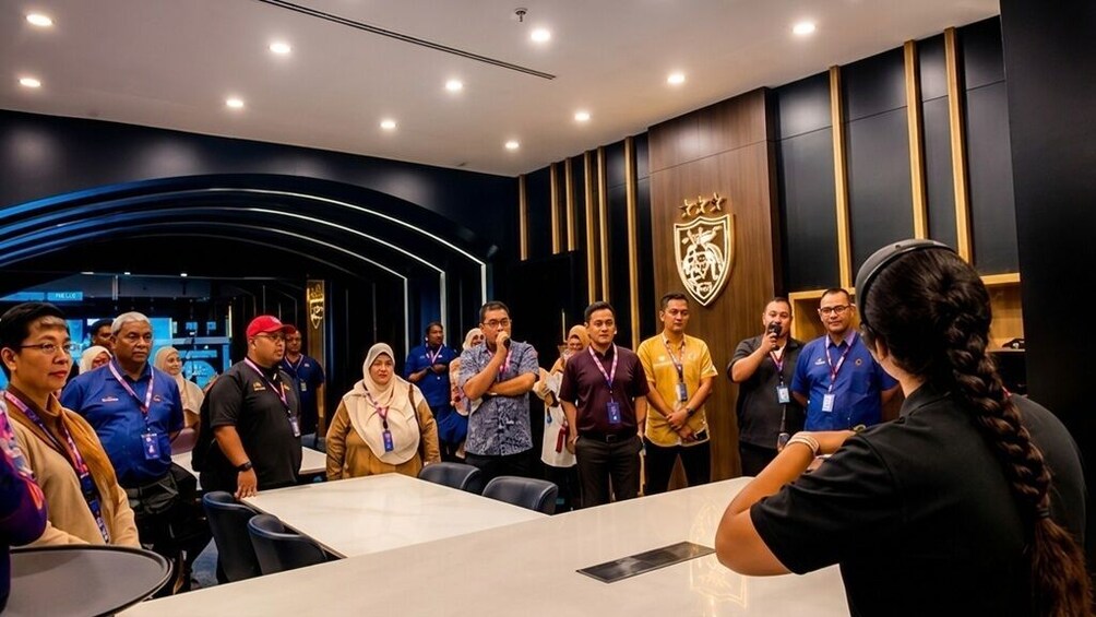 A group of people in a modern conference room with a logo on the wall. 3