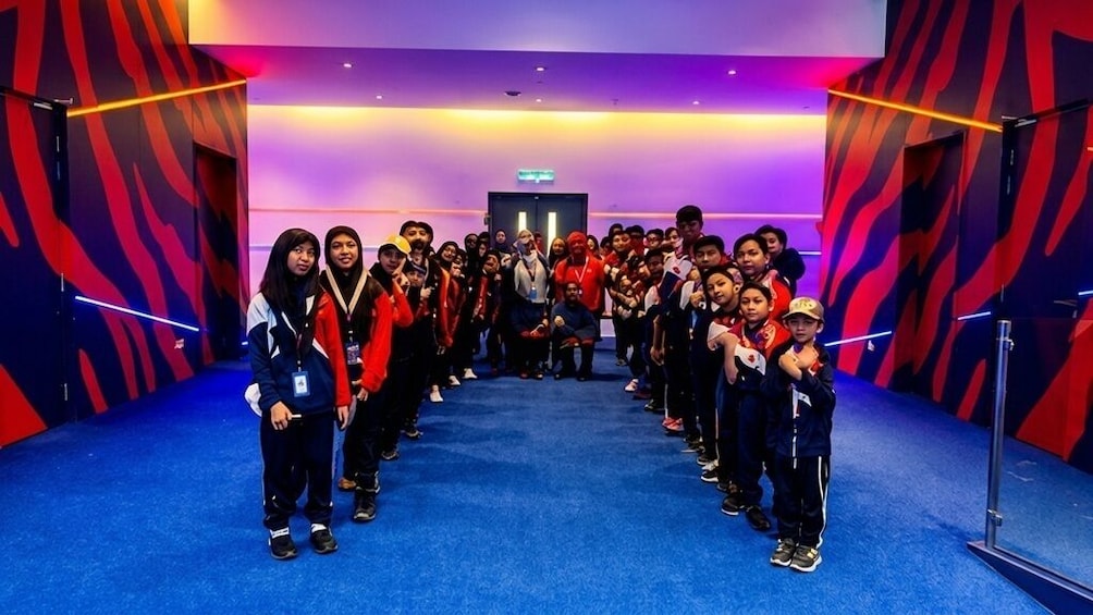 A group of people standing in a line in a room with a blue carpet and red and black patterned walls. 5