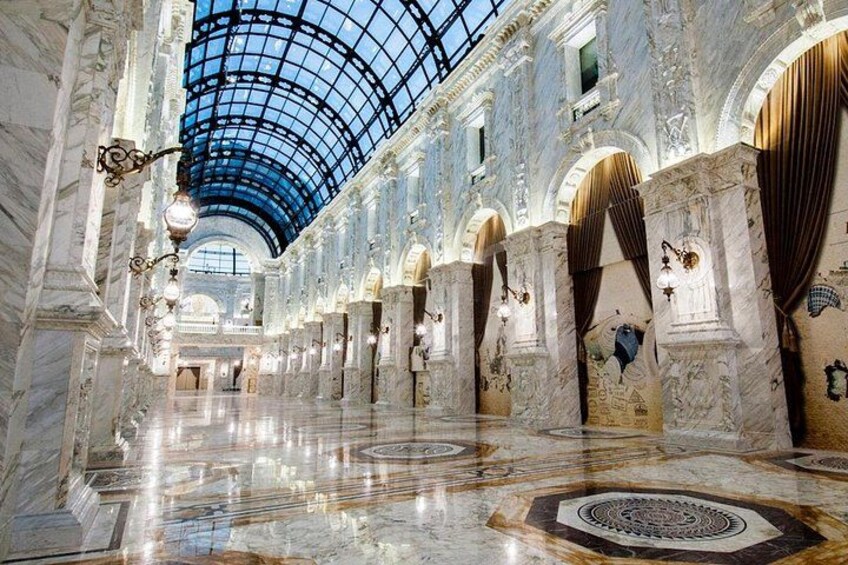 Un interior imponente de mármol con cúpula de cristal, columnas ornamentadas y baldosas de suelo con diseños. 3