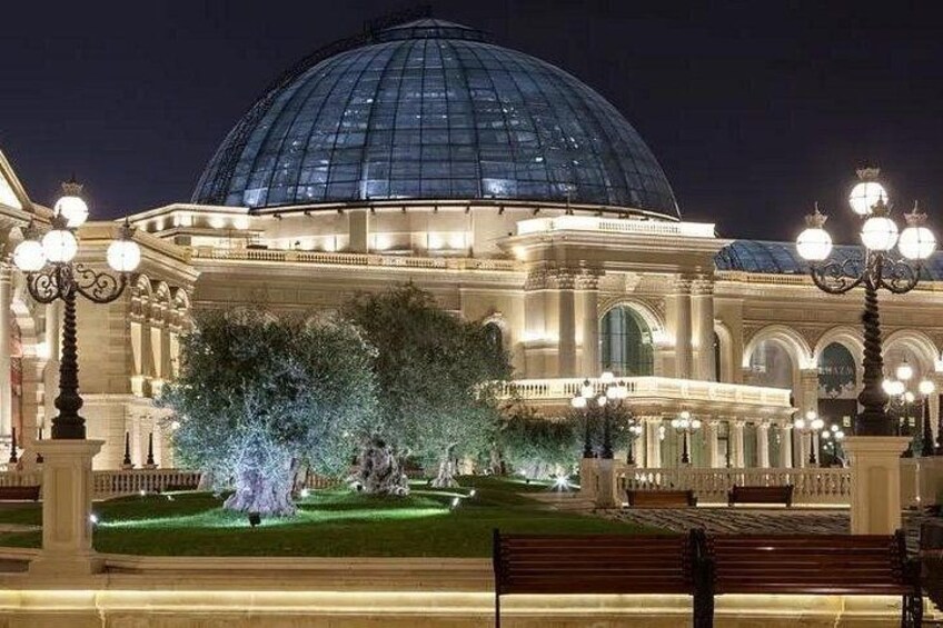 Un edificio imponente con una gran cúpula y arquitectura clásica, rodeado de árboles bien iluminados y bancos. 2