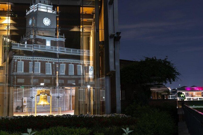 A historic building with a clock tower, illuminated windows, and a well-maintained garden. 5
