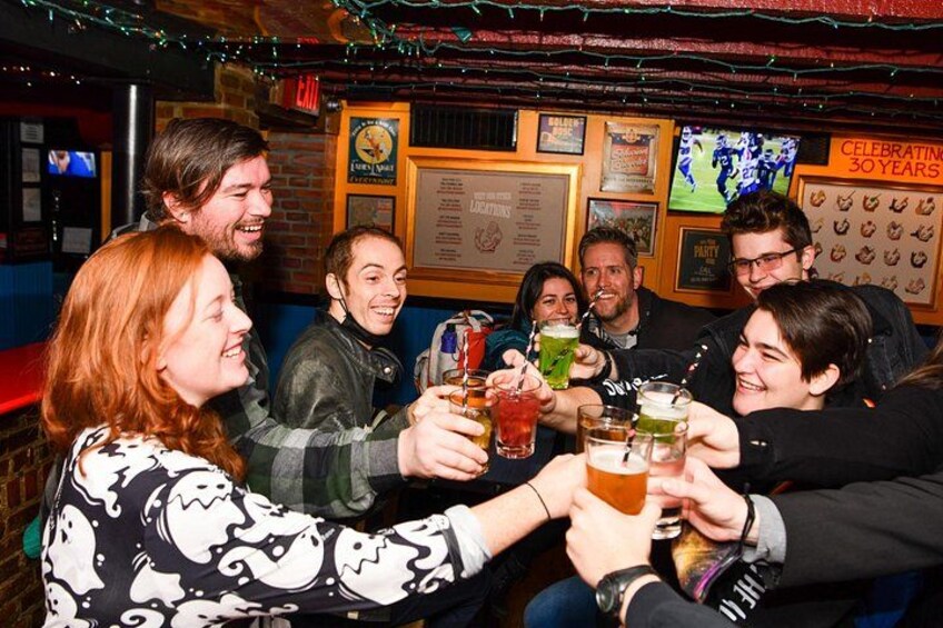 A group of people toasting with drinks in a bar with festive decorations and a 'Celebrating 30 Years' sign. 1