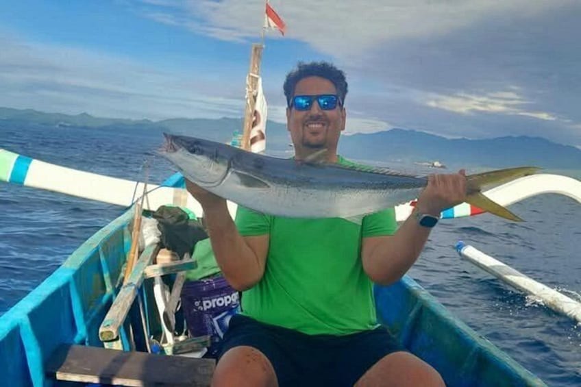 A person holding a fish on a boat with a mountainous landscape in the background. 3
