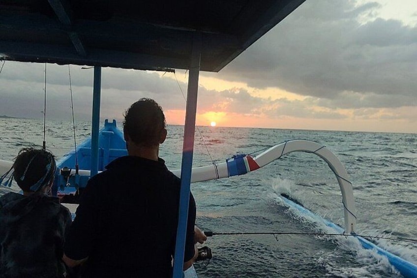 A boat with a person steering, the ocean, and a sunset. 2