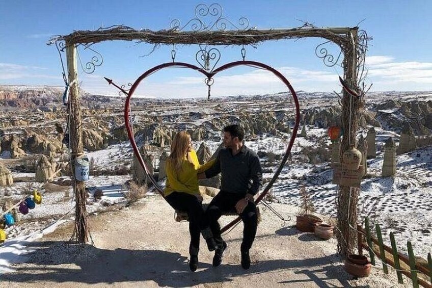 A couple embracing under a heart-shaped arch with a mountainous landscape in the background. 5