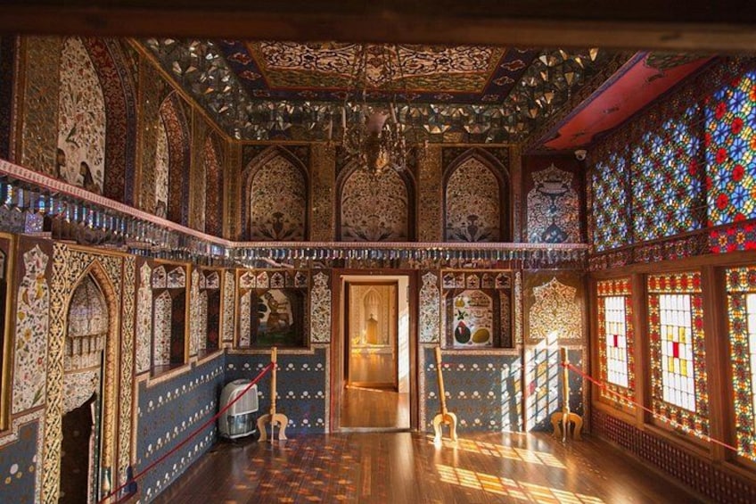 Un intérieur richement décoré, avec des motifs complexes sur les murs et le plafond, un escalier et un petit chien. 2