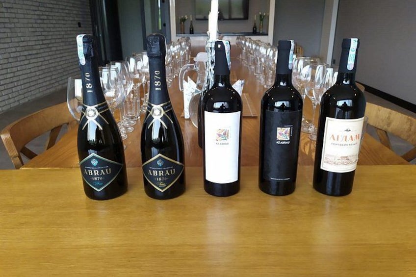 Une table avec cinq bouteilles de vin et plusieurs verres à vin vides. 5