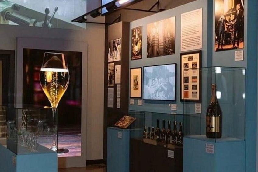 Une salle de dégustation de vins avec un verre de vin, des bouteilles de vin et des affiches d'information. 1