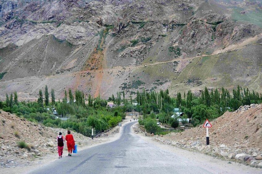 A road with a sharp bend, surrounded by rocky terrain and sparse vegetation. 3