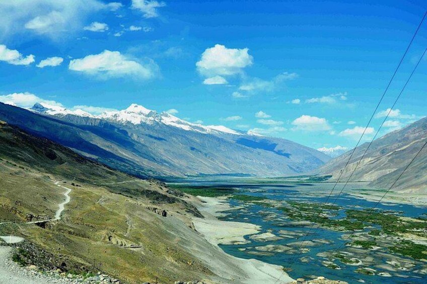A mountainous landscape with a river, snow-capped peaks, and a clear sky. 5