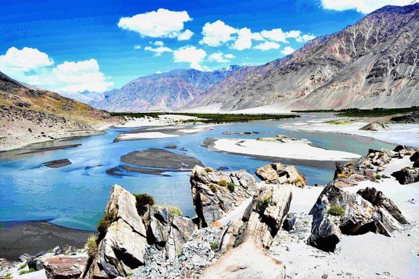 A river winding through a mountainous landscape with rocky outcrops and distant peaks. 1