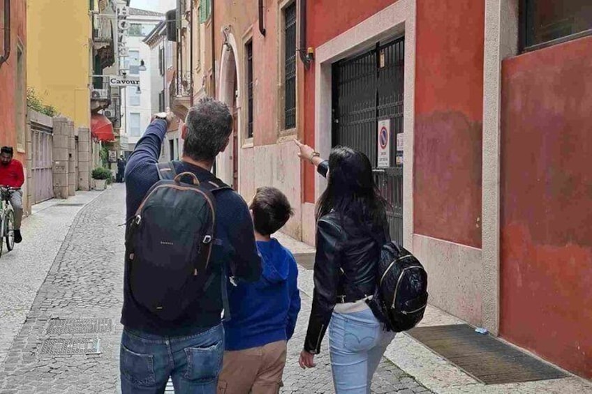 A narrow street with buildings, a man pointing at something, and a child. 1