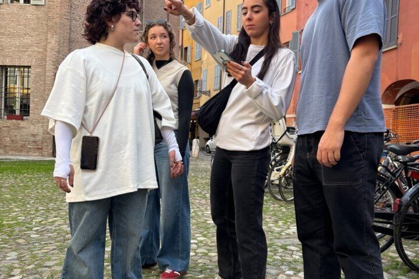 A group of people standing on a cobblestone street with bicycles parked in the background. 2