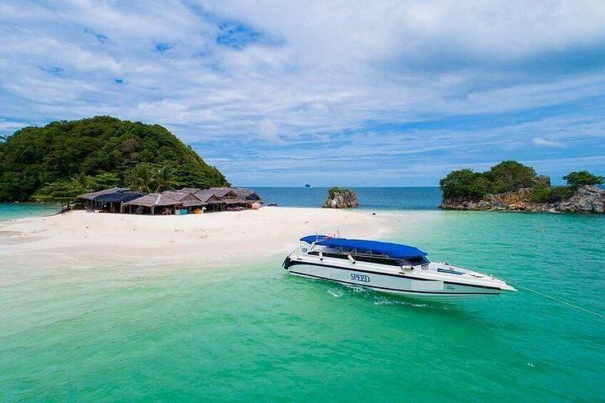 Un bateau appelé SPEED navigue sur des eaux turquoise, près d’une plage de sable blanc bordée de cabanes et d’une île couverte de forêts. 5