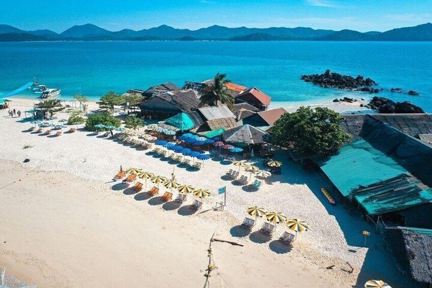 Une plage avec des parasols, des chaises longues et des constructions à toits de chaume. 2