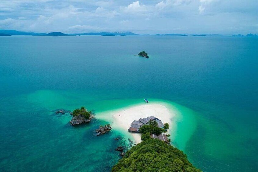 Vue aérienne d’un lagon turquoise avec une petite île et une plage de sable. 1