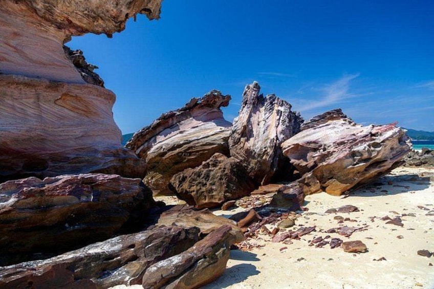 A rocky shoreline with large boulders and a clear blue sky. 2